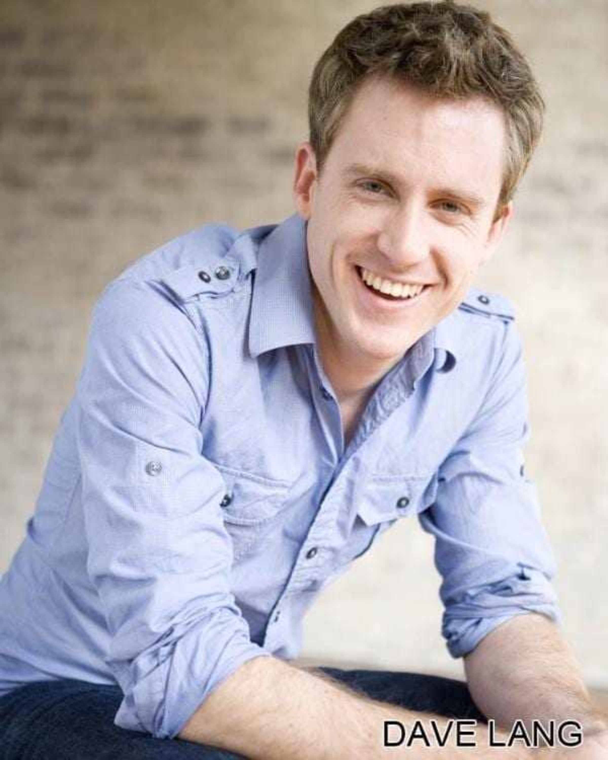 Smiling male wedding entertainer in a light blue shirt posing for a professional portrait.