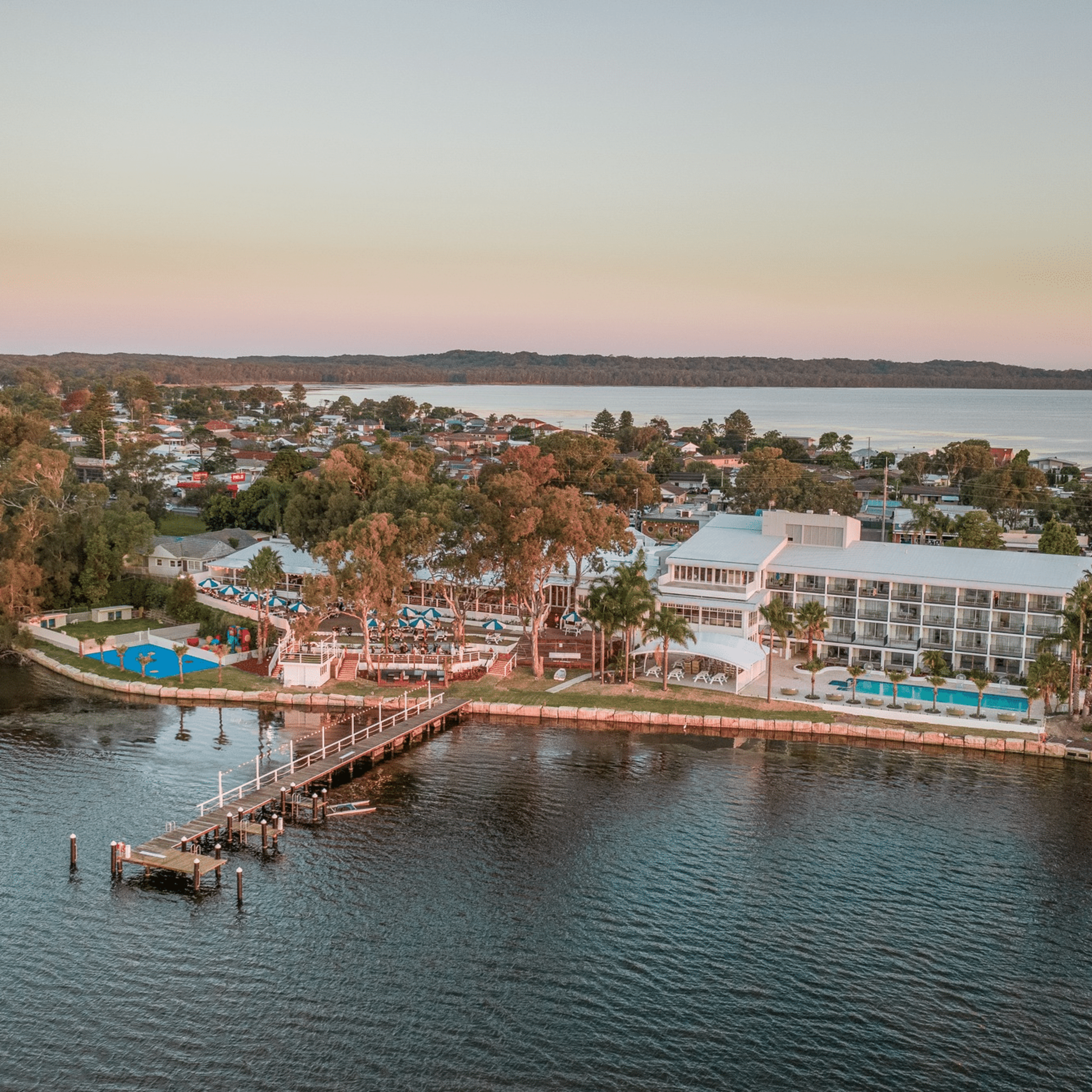 Aerial view of a waterfront resort and pier at sunset, ideal as a lakeside wedding venue.