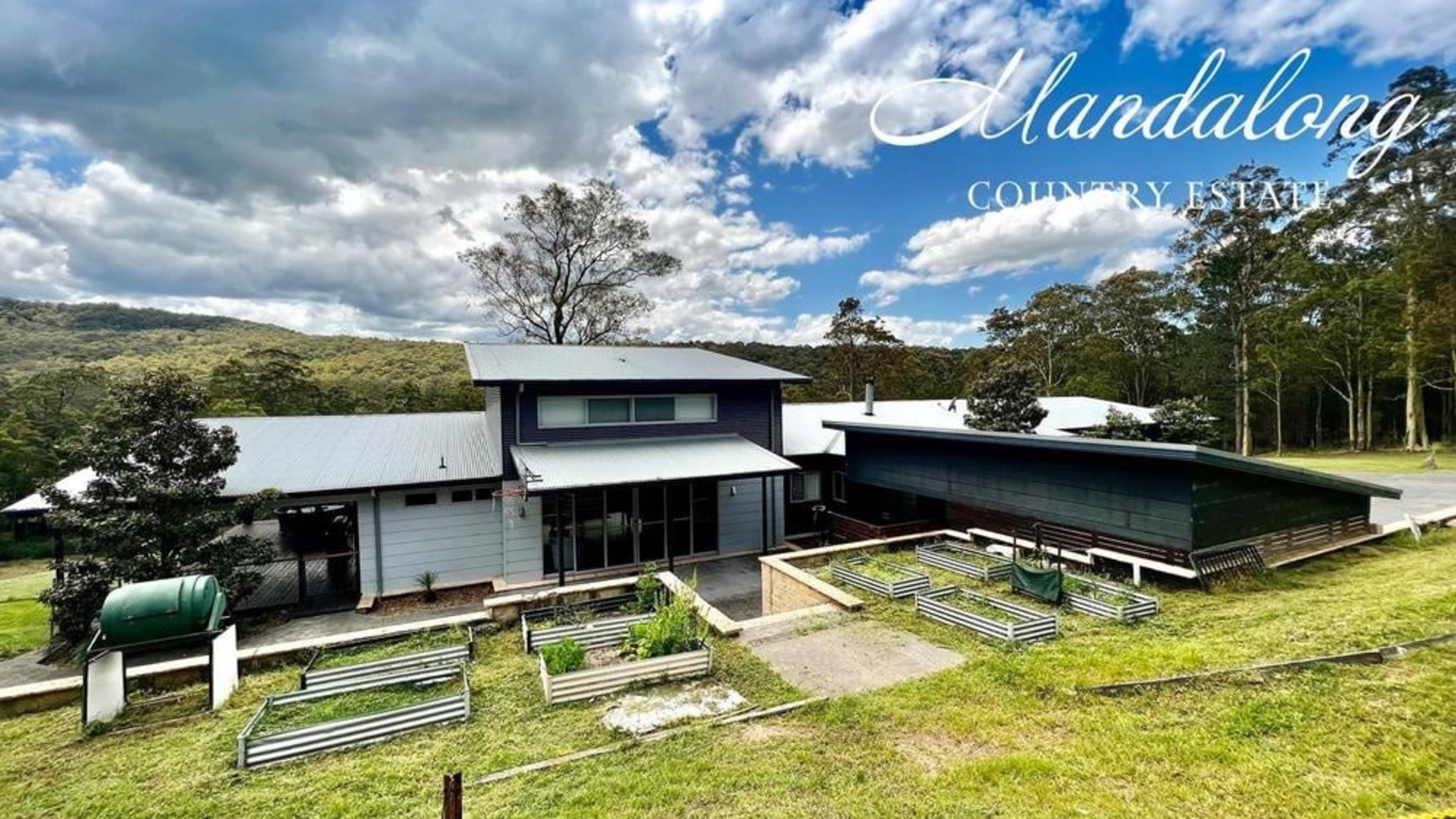 Modern country estate wedding venue set on rolling green hills under a dramatic cloudy sky.