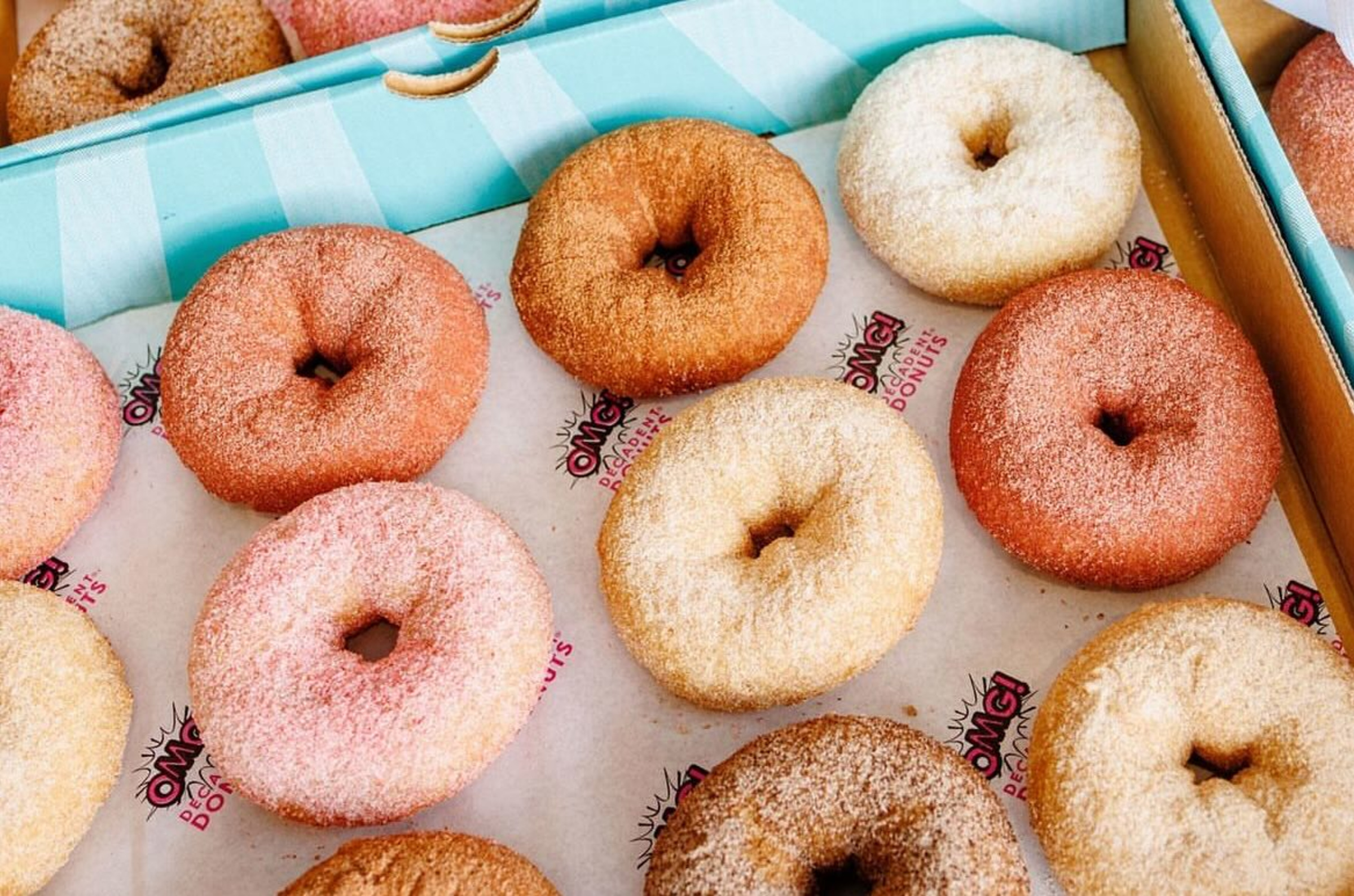 Assorted sugar-coated donuts arranged in colorful bakery boxes, ideal for a wedding dessert display.