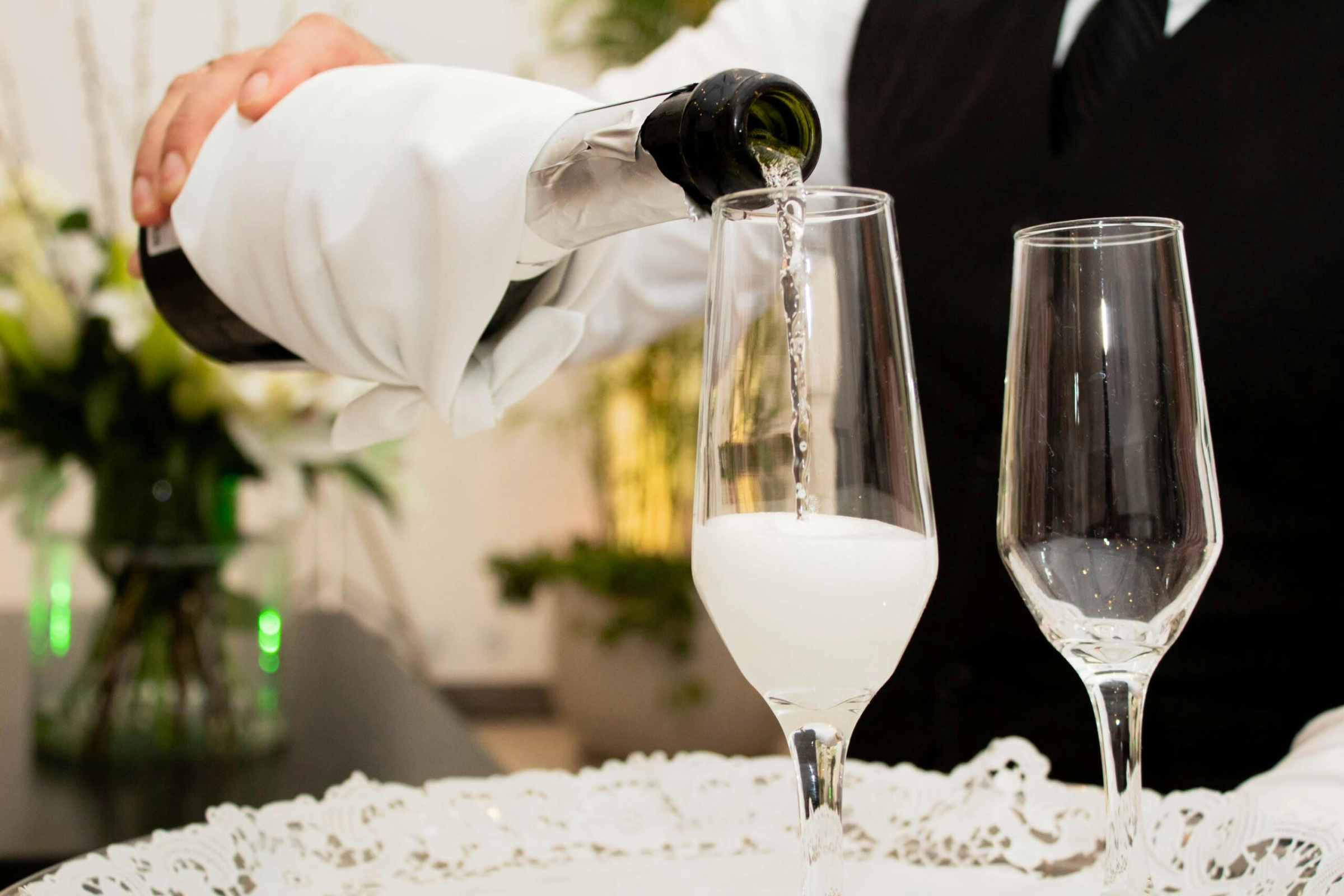 Server pours champagne into flutes on an elegant tray at a wedding reception
