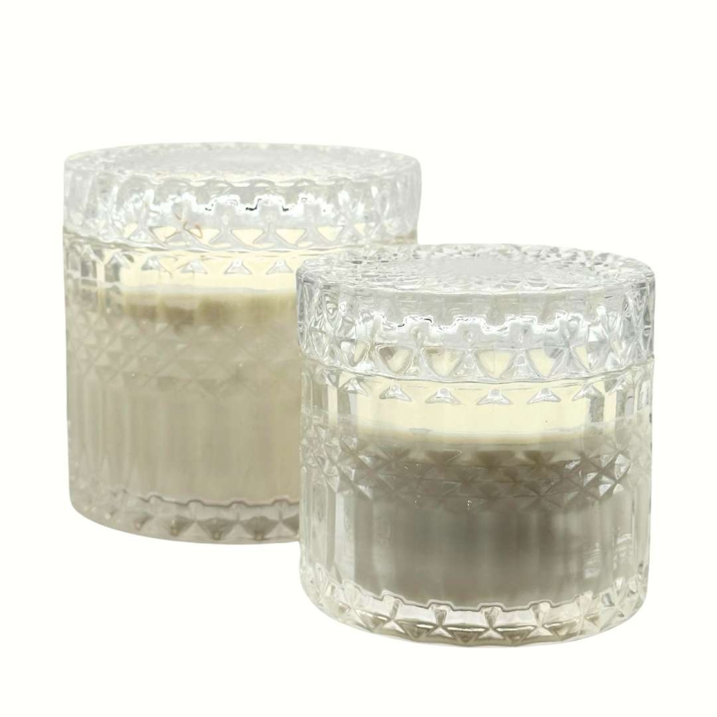 Two white candles in ornate clear glass jars suitable for elegant wedding table decor.