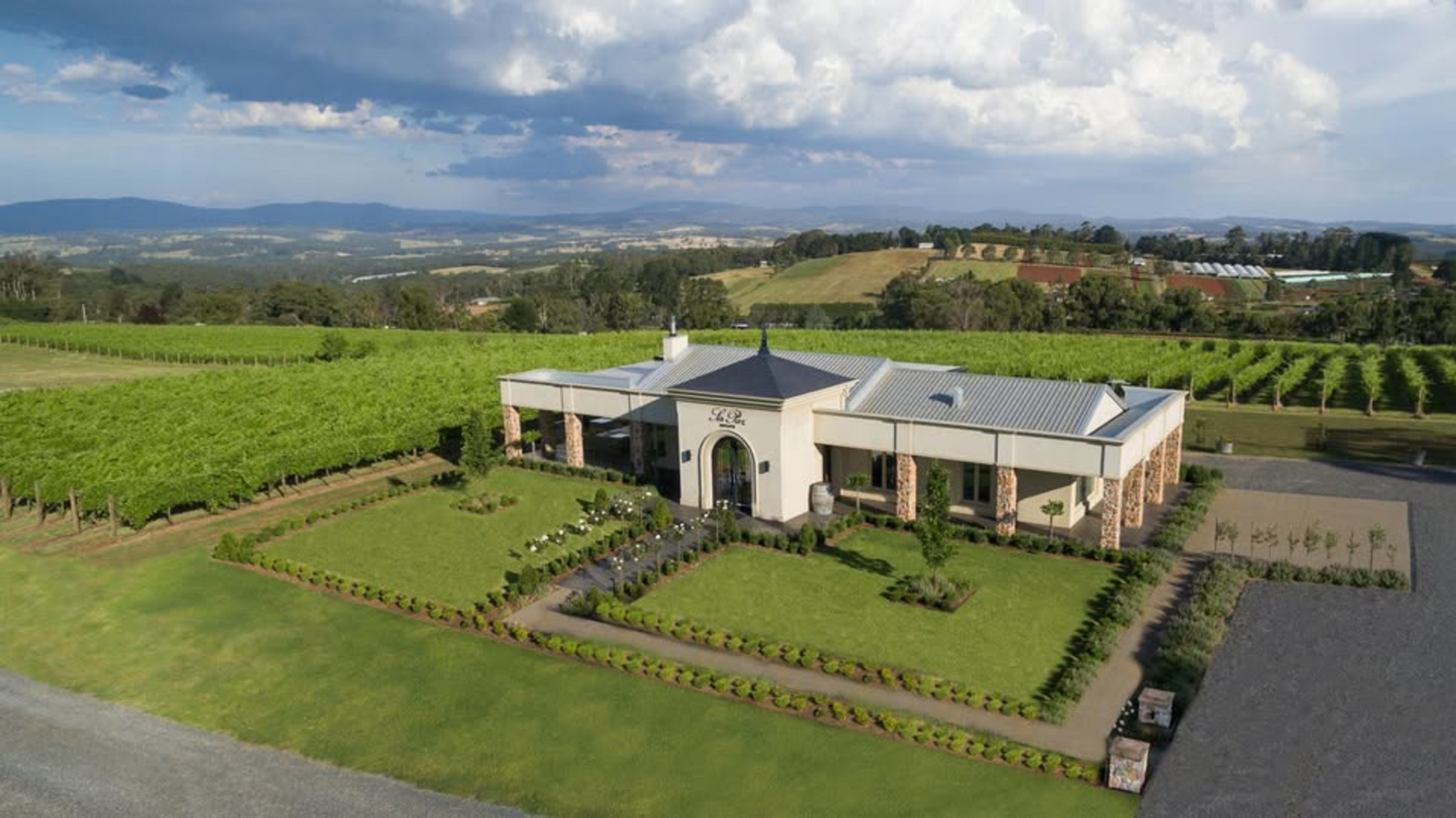 A modern winery estate wedding venue surrounded by lush vineyards and rolling countryside hills.