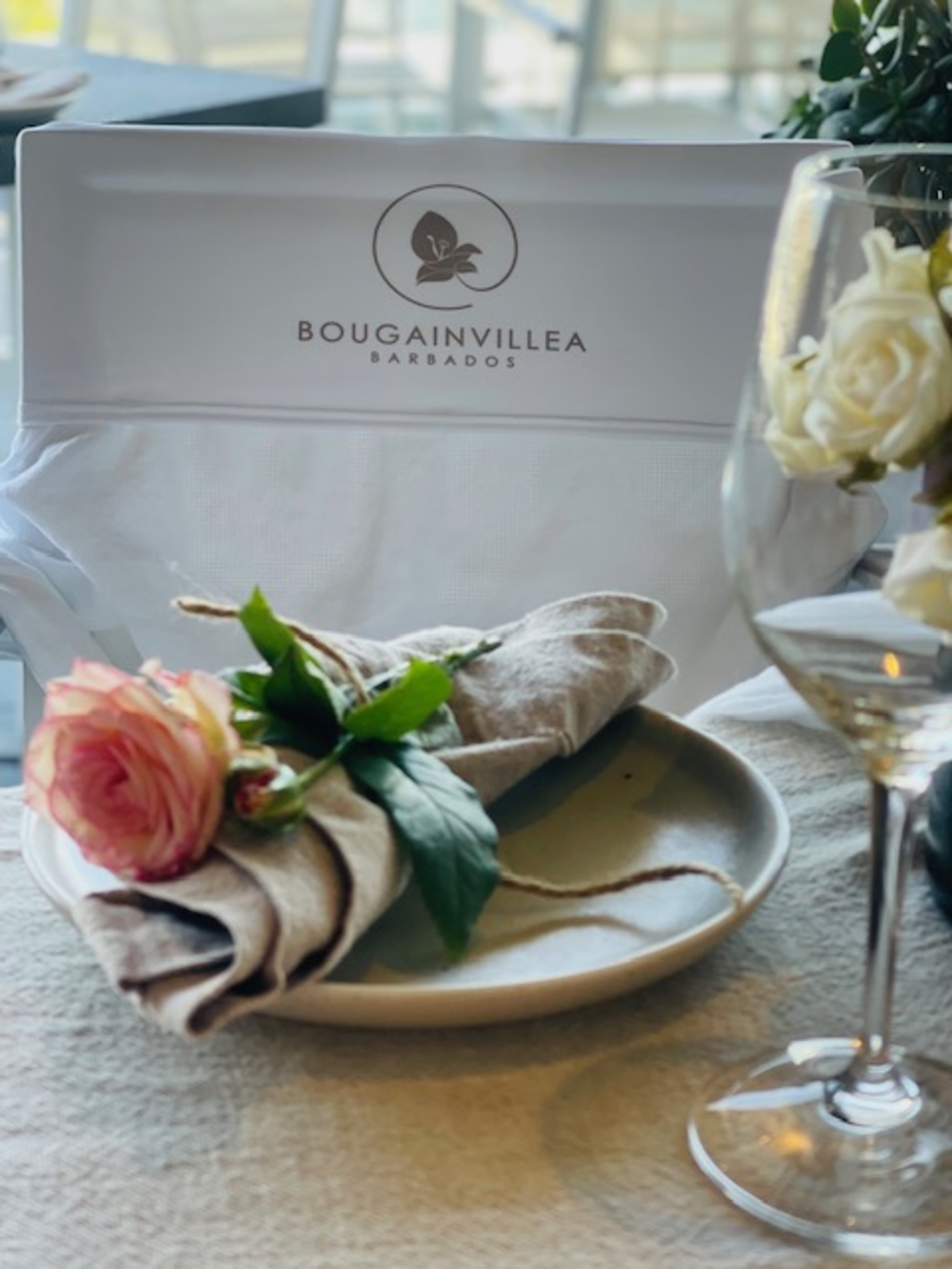 Elegant wedding table setting at Bougainvillea Barbados with rose-adorned napkin and wine glass.