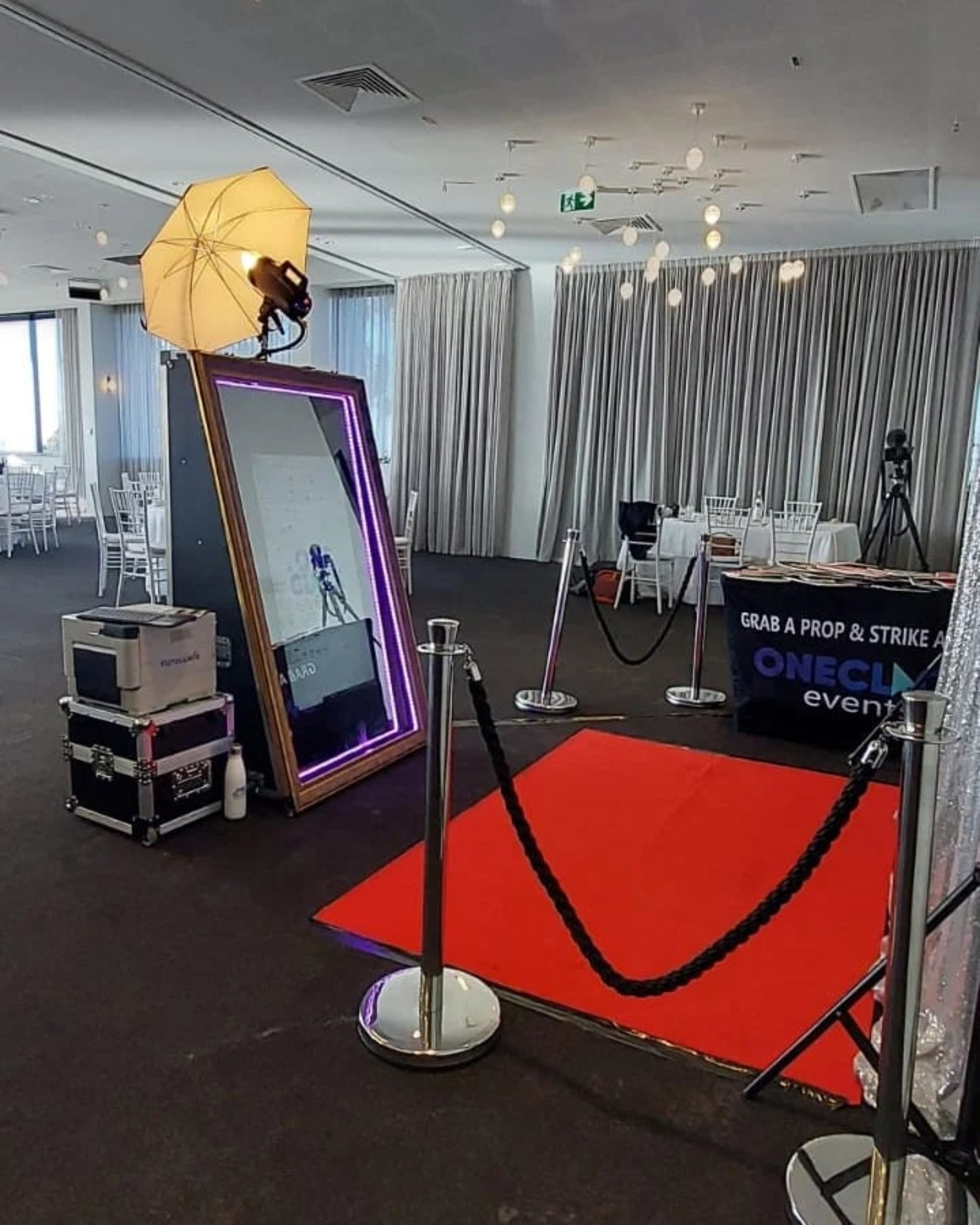 Red carpet mirror photo booth setup in a modern wedding reception venue.