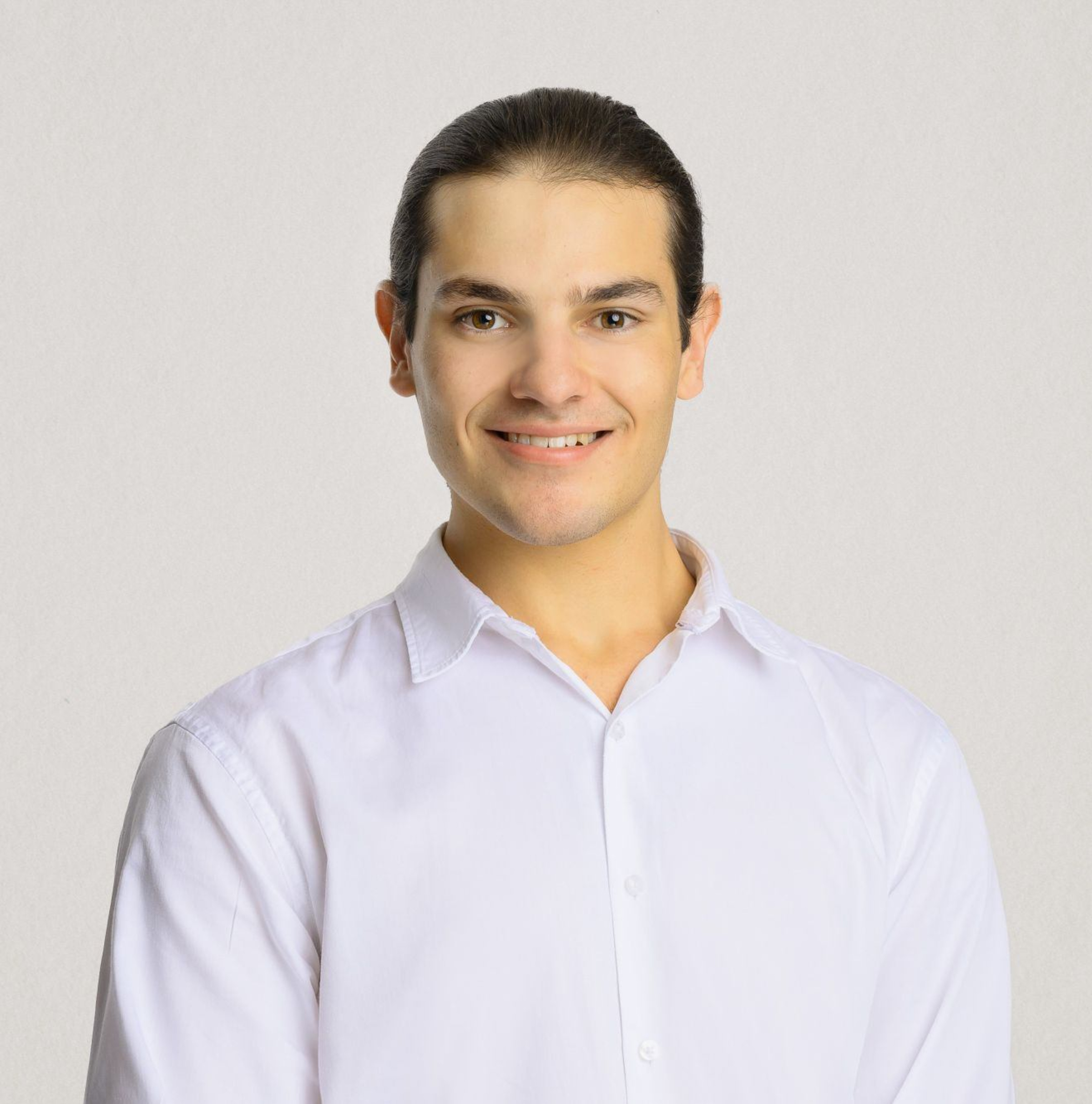 Smiling wedding vendor in a white shirt posing for a professional headshot on a light background.