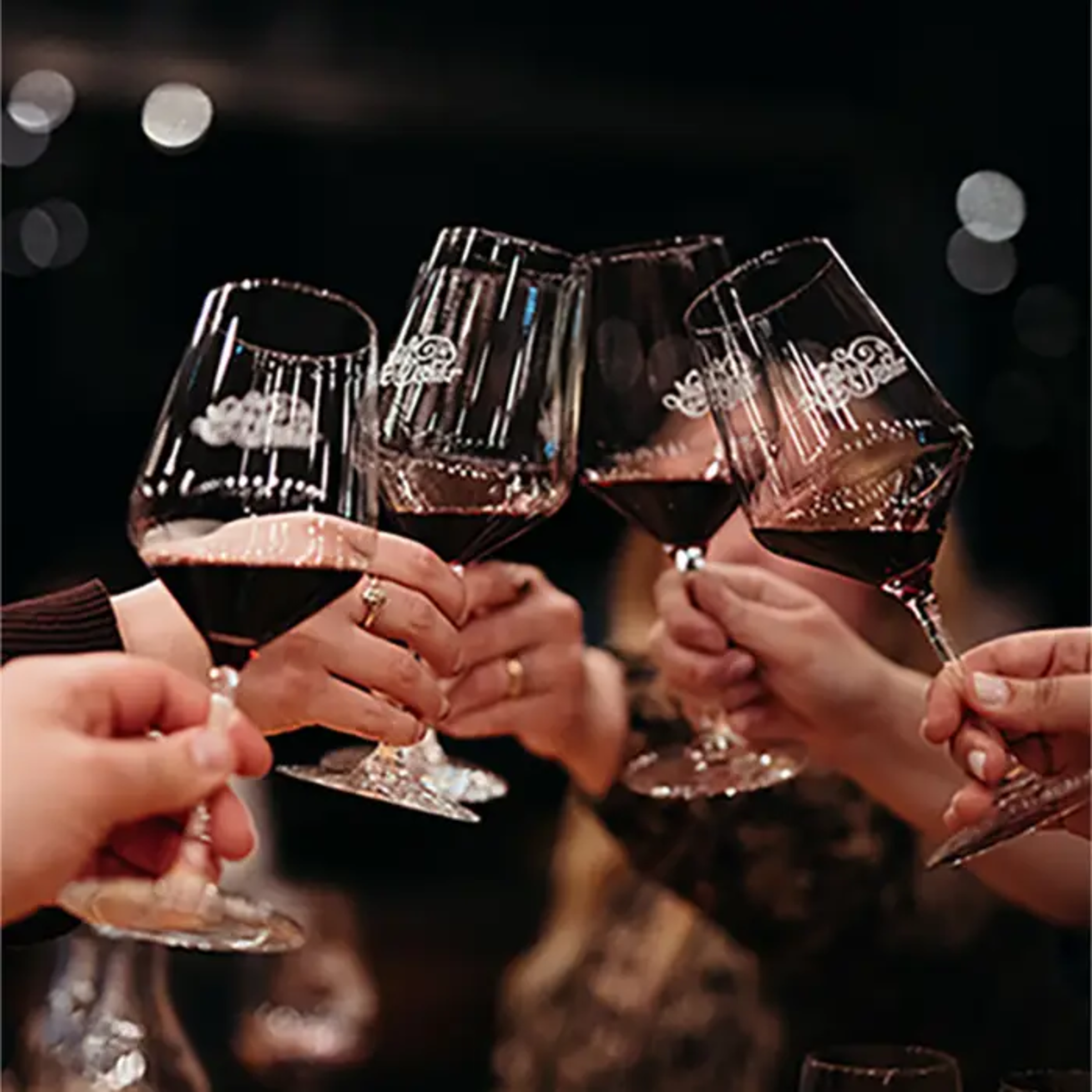 Guests raise red wine glasses in a celebratory toast at a wedding reception.
