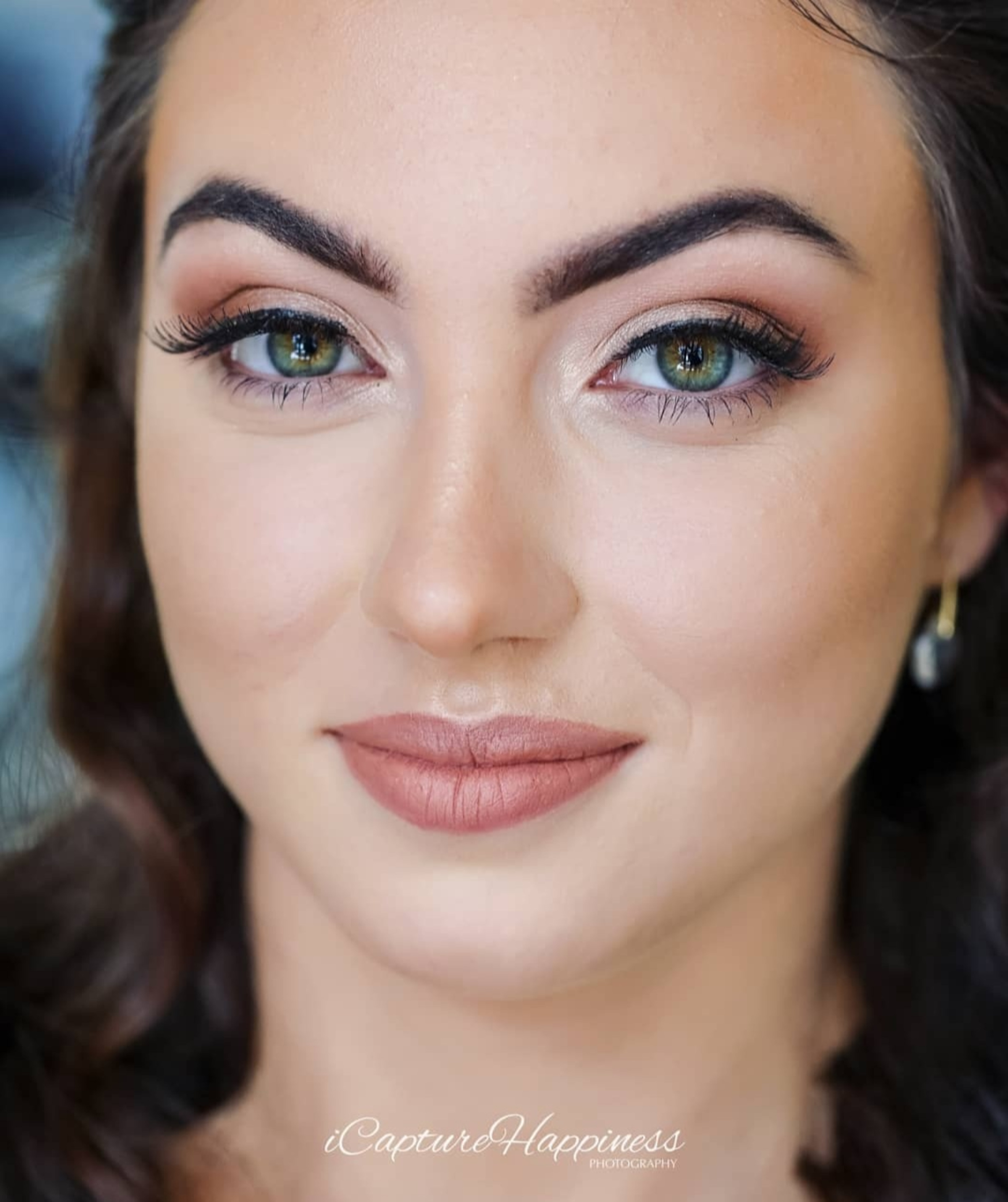 Close-up bridal portrait showcasing soft glam makeup and green eyes.
