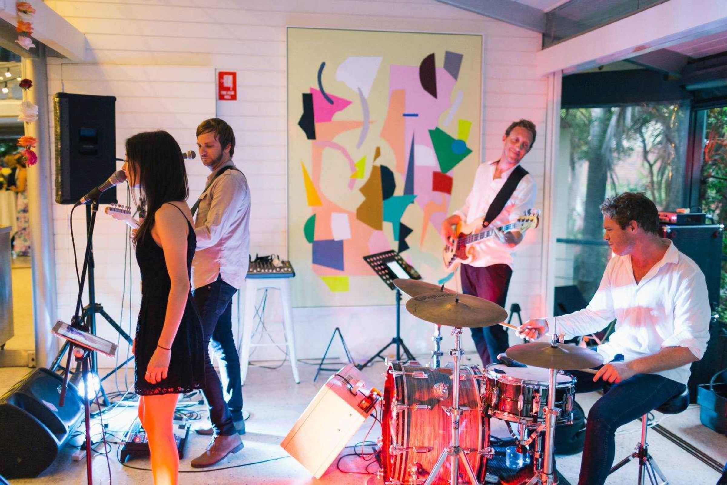 Live band performing indoors at a wedding reception with colorful lighting and instruments.