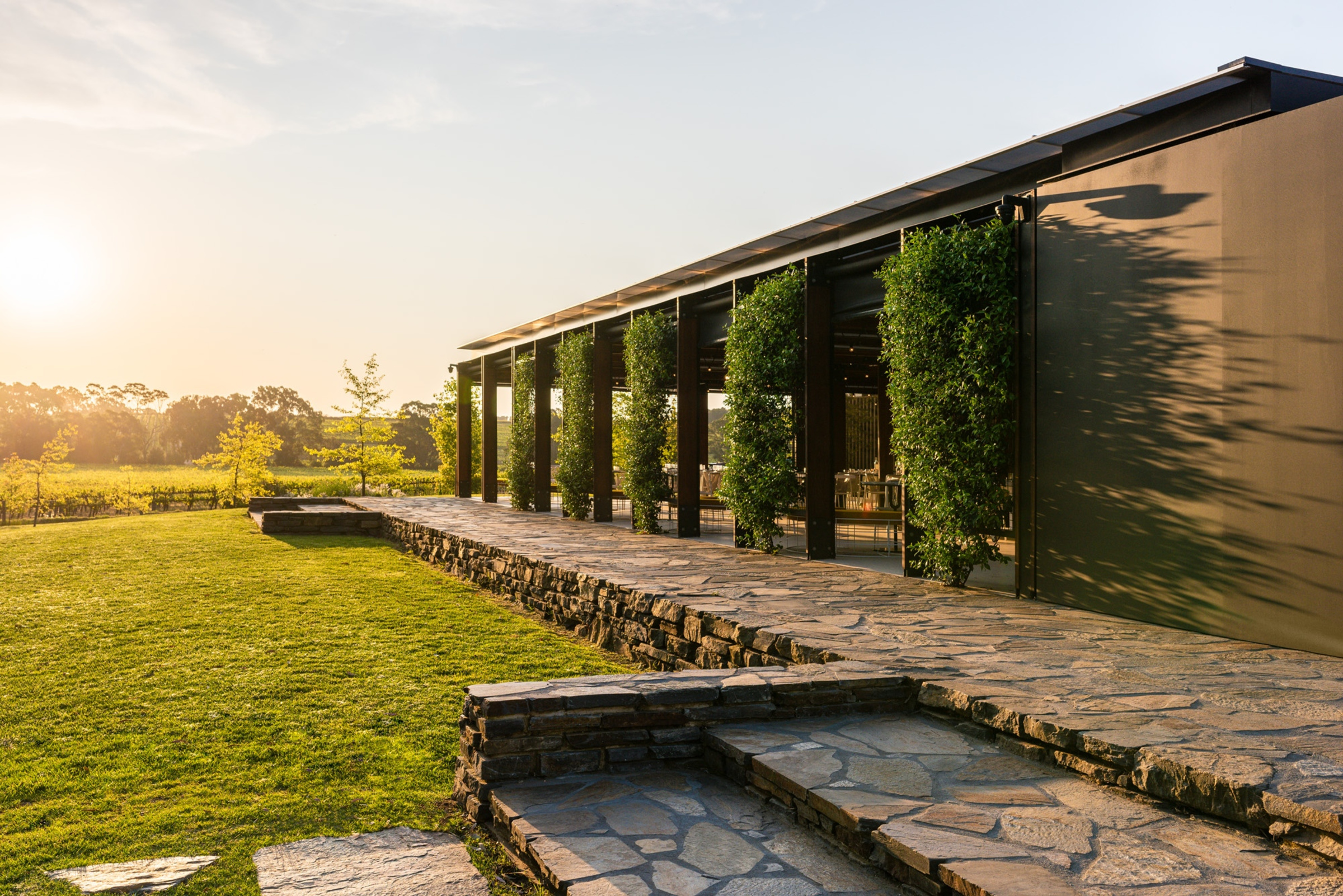 Modern open-air wedding venue with stone terrace and greenery at sunset.