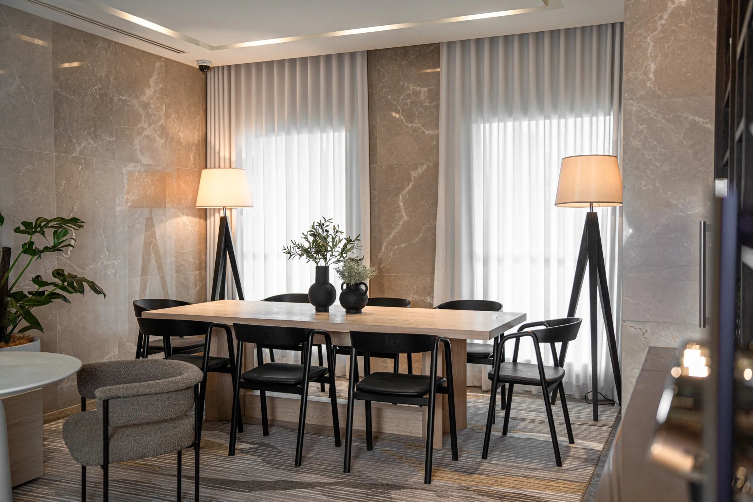 Modern lounge-style room with a wooden table, black chairs, and floor lamps, ideal for an intimate wedding gathering.