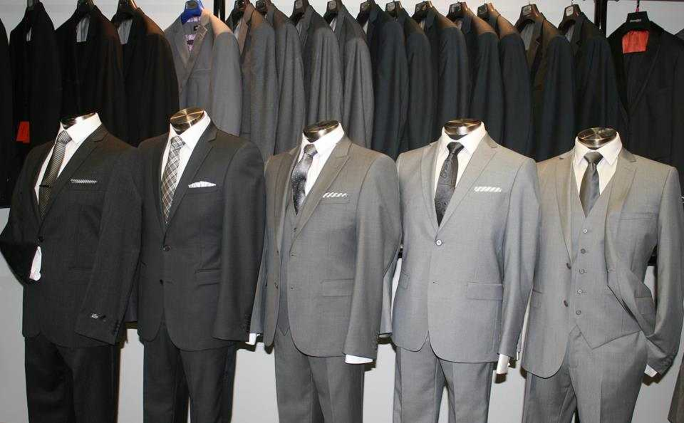 Row of mannequins displaying grey and black men's suits for wedding or formalwear.