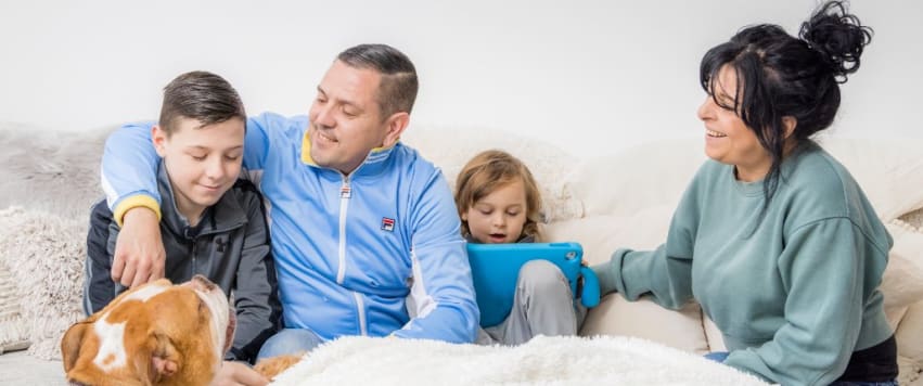 Two adults with two children and dog sitting at home
