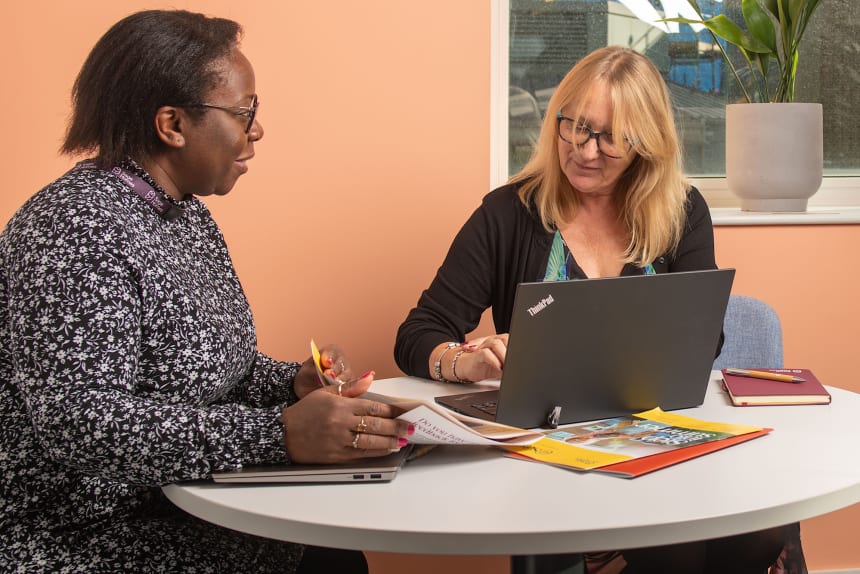 two women working beside a laptop