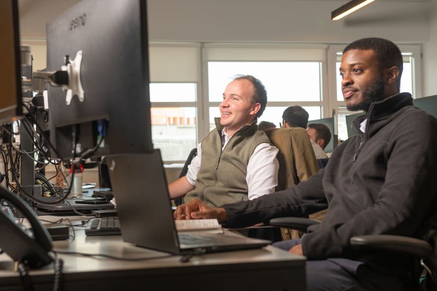 Two smiling men sitting in front of desktop