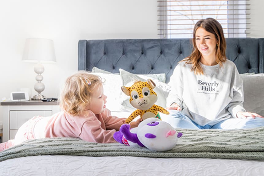Lady and child sitting on bed with toy