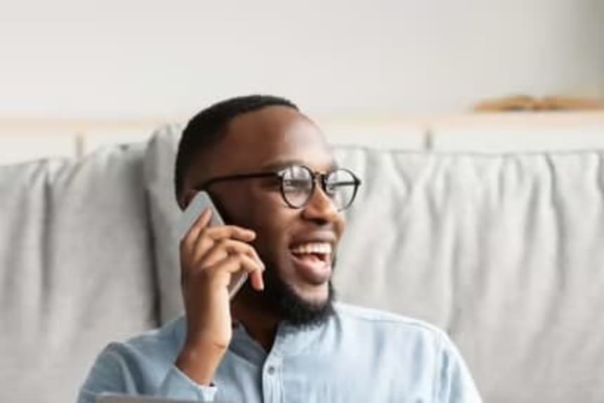 Man sitting on floor on the phone with laptop