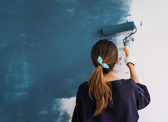 Women painting wall blue