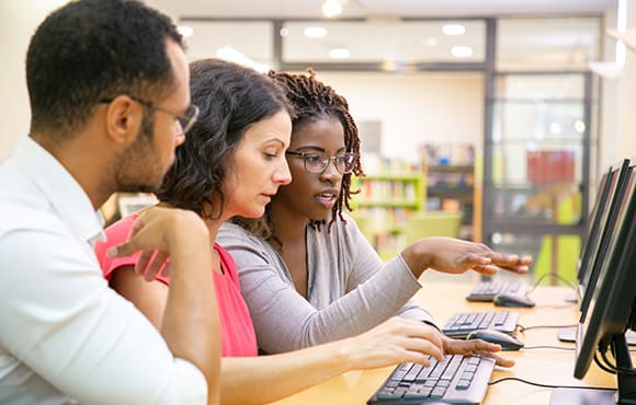 Two women and man looking at laptop