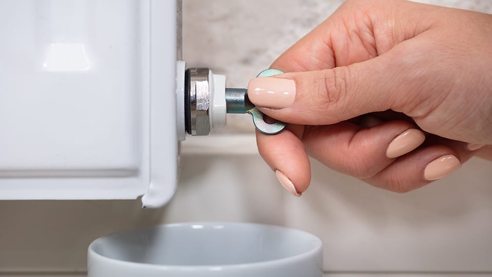 Female hand turning radiator key to bleed air from system
