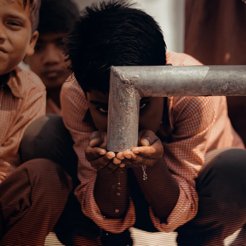 humanitarian aid - boy drinking water from pipe