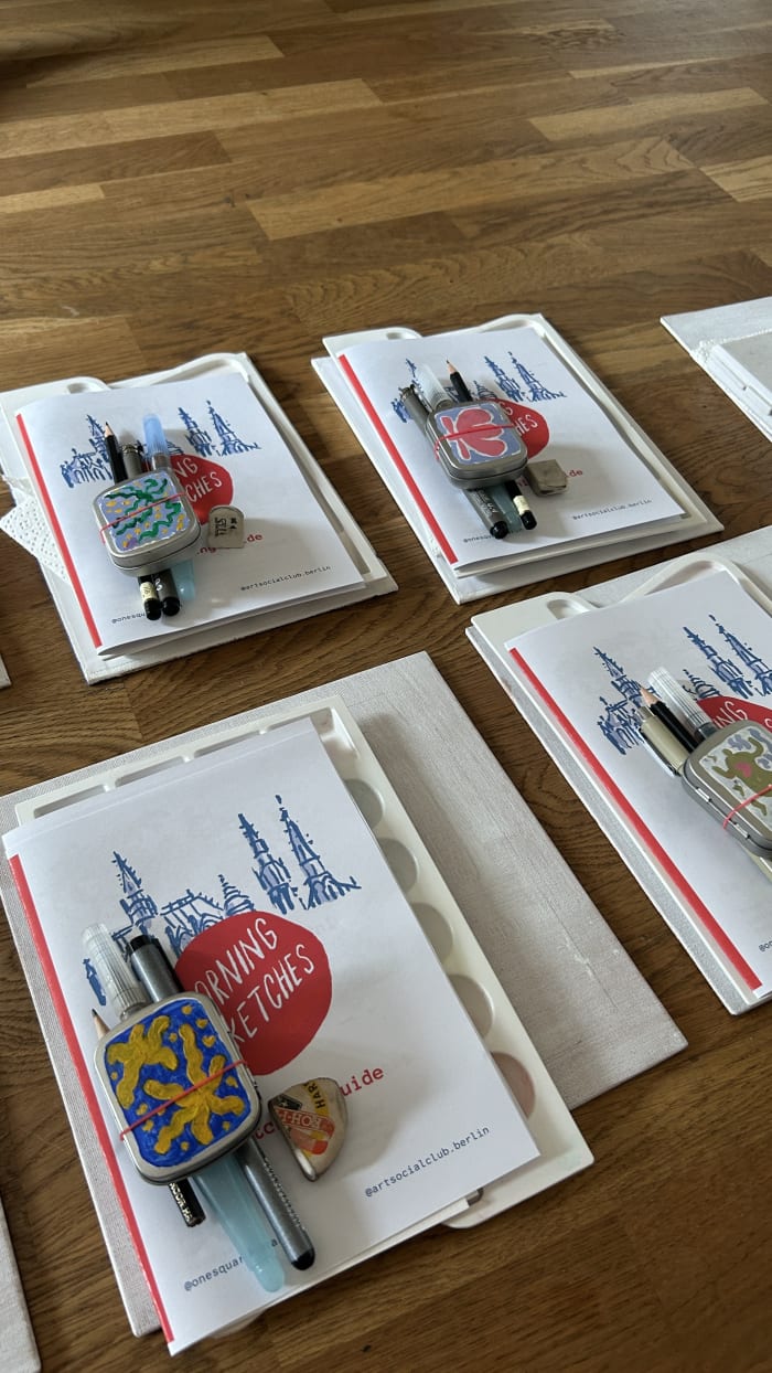 Watercolour kits and postcards laid out on a wooden floor