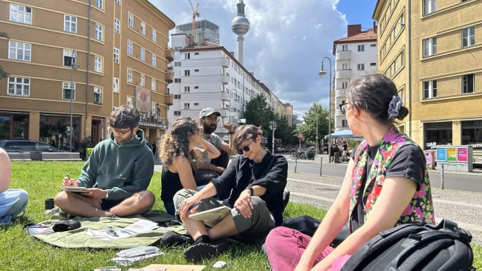 Group sketching in a square with the TV tower behind