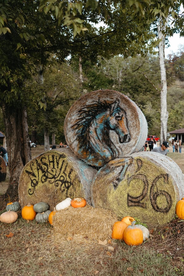 Painted hay bales with a horse and “Nashville ’26” surrounded by pumpkins