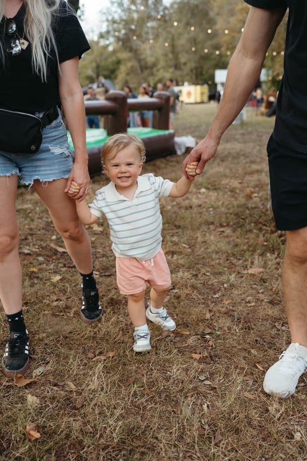 Parents walking hand in hand with their toddler