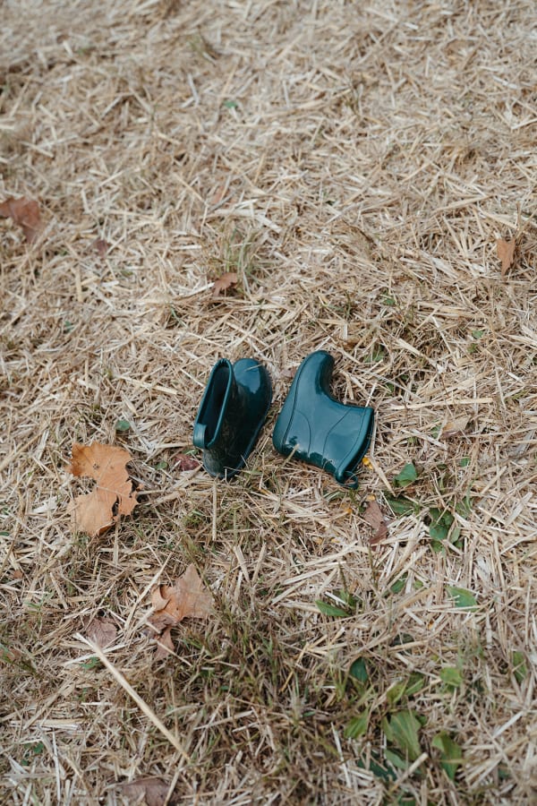 Tiny green rain boots left in the grass