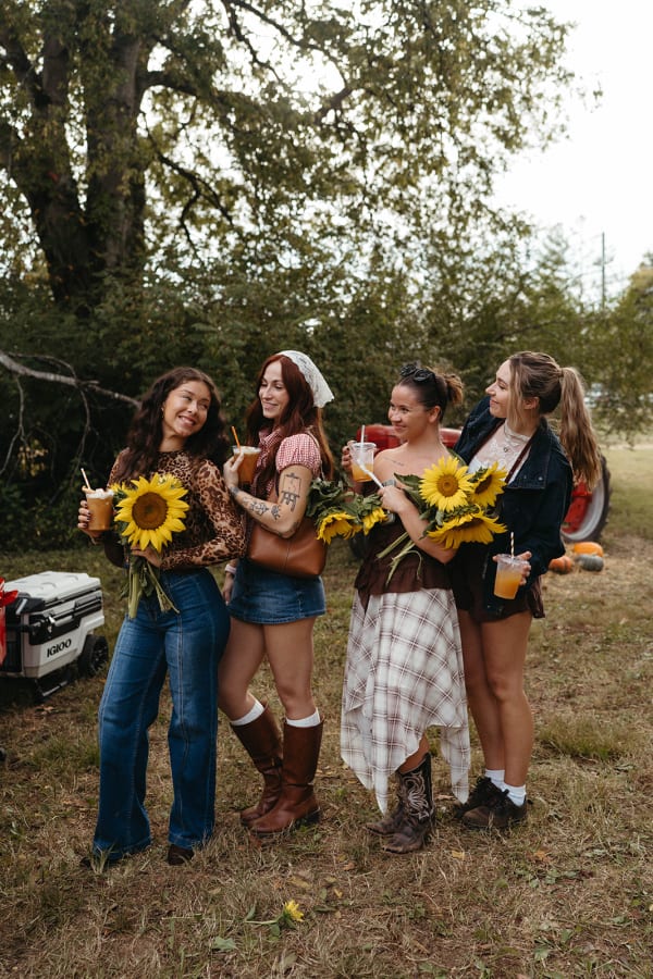 Four friends holding sunflower bouquets