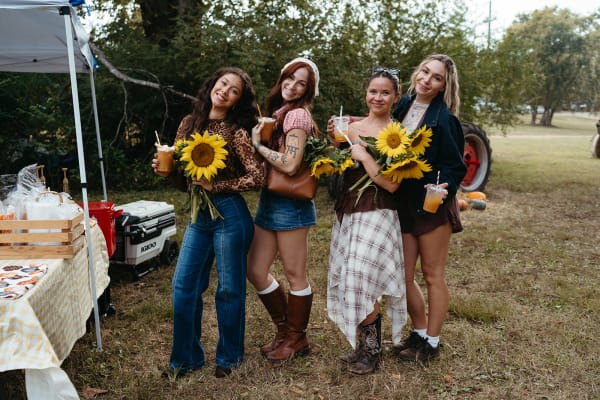 Four friends holding sunflower bouquets