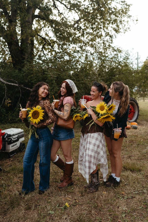 Four friends holding sunflower bouquets