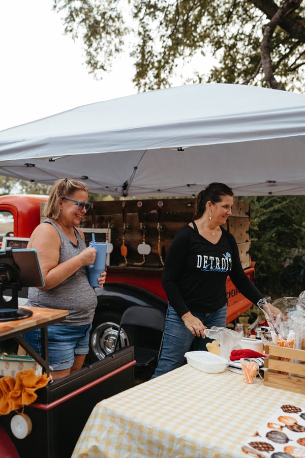 Vendors serving guests at a stand beside a vintage red truck