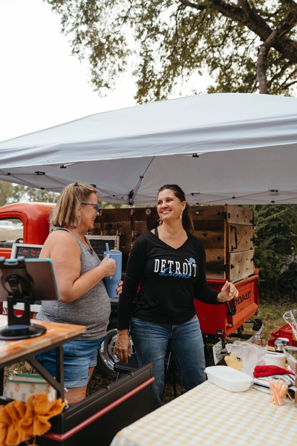 Vendors serving guests at a stand beside a vintage red truck