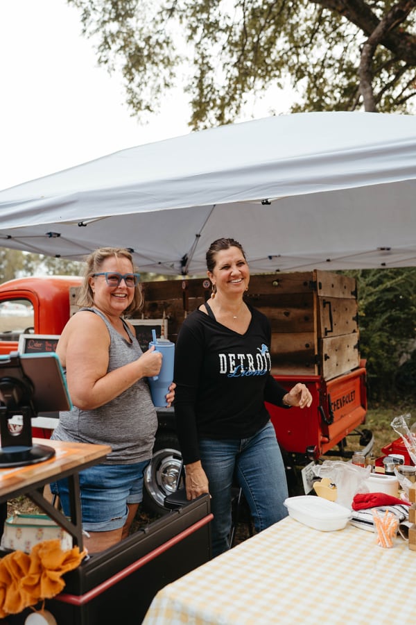 Vendors serving guests at a stand beside a vintage red truck