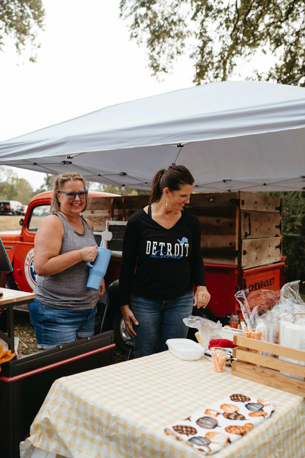 Vendors serving guests at a stand beside a vintage red truck