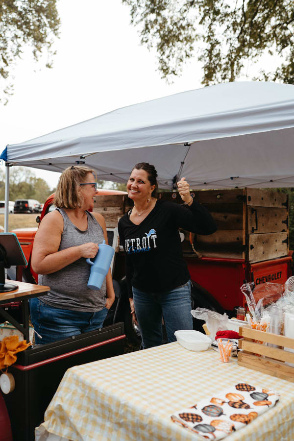 Vendors serving guests at a stand beside a vintage red truck