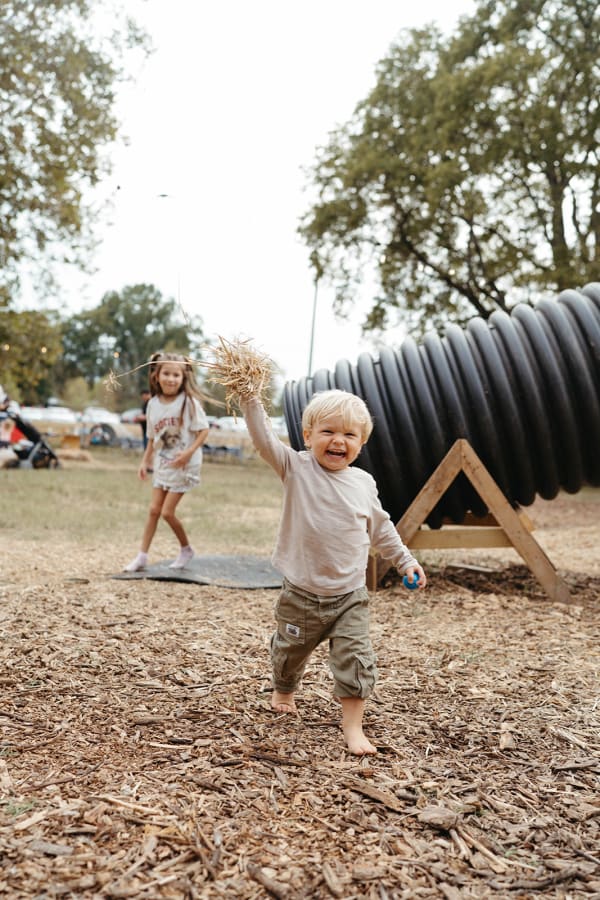 Toddler laughing and running near the play tunnel