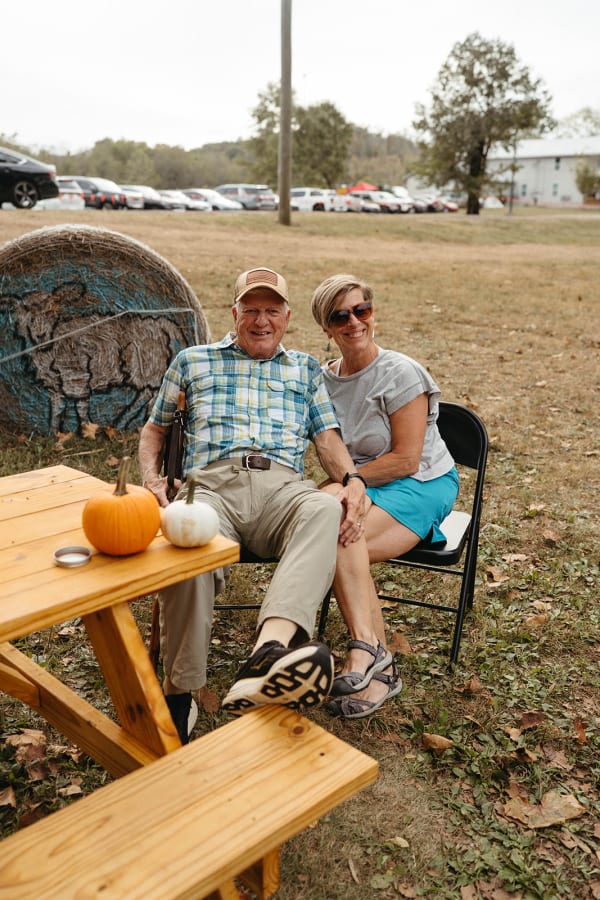 Couple relaxing at a picnic table with a pumpkin