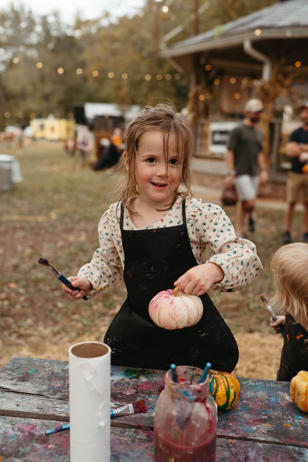 Smiling girl holding up her painted pumpkin