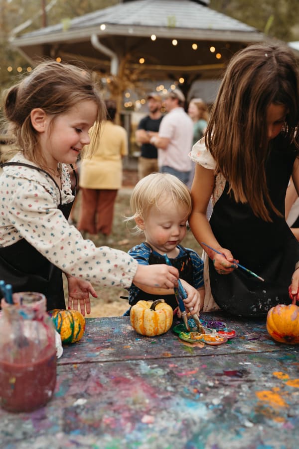 Kids painting mini pumpkins at the paint table