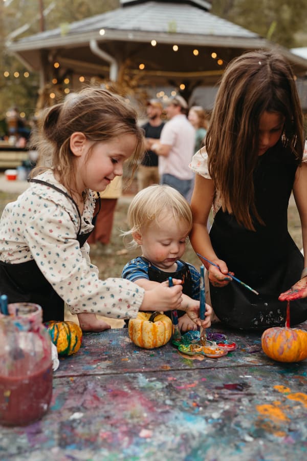 Kids painting mini pumpkins at the paint table