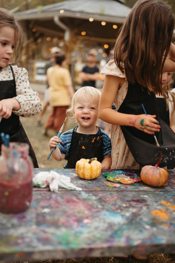 Kids painting mini pumpkins at the paint table