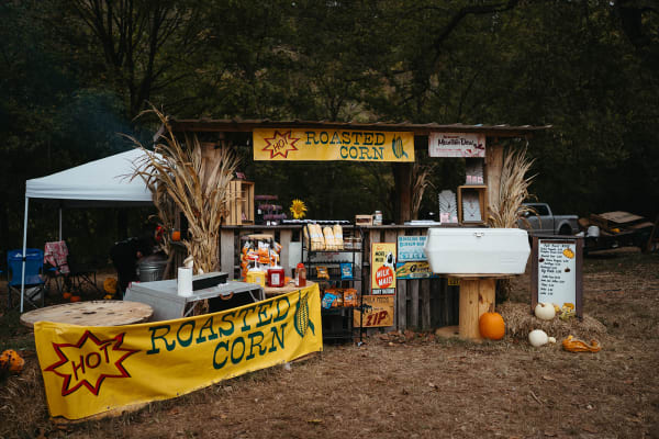 Roasted corn stand decorated with corn stalks and pumpkins