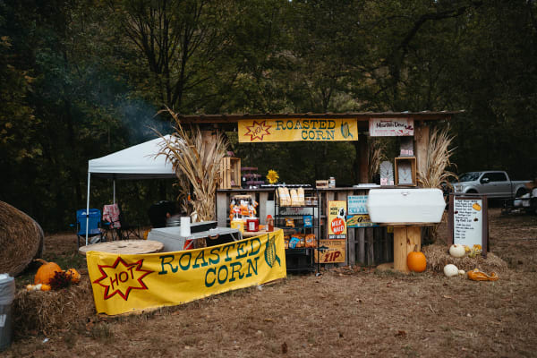 Roasted corn stand decorated with corn stalks and pumpkins