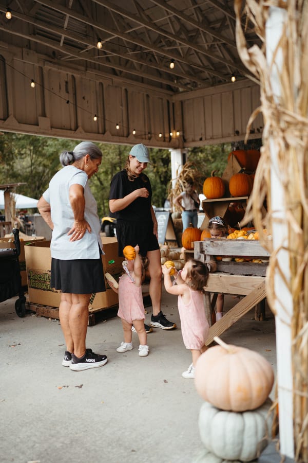 Little girls picking pumpkins with their family under the pavilion