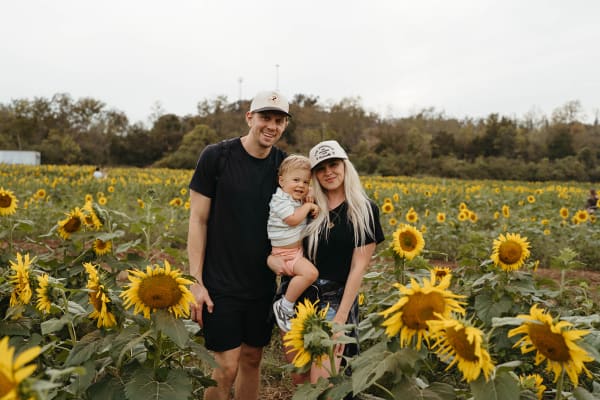 Family with a baby posing in the sunflowers