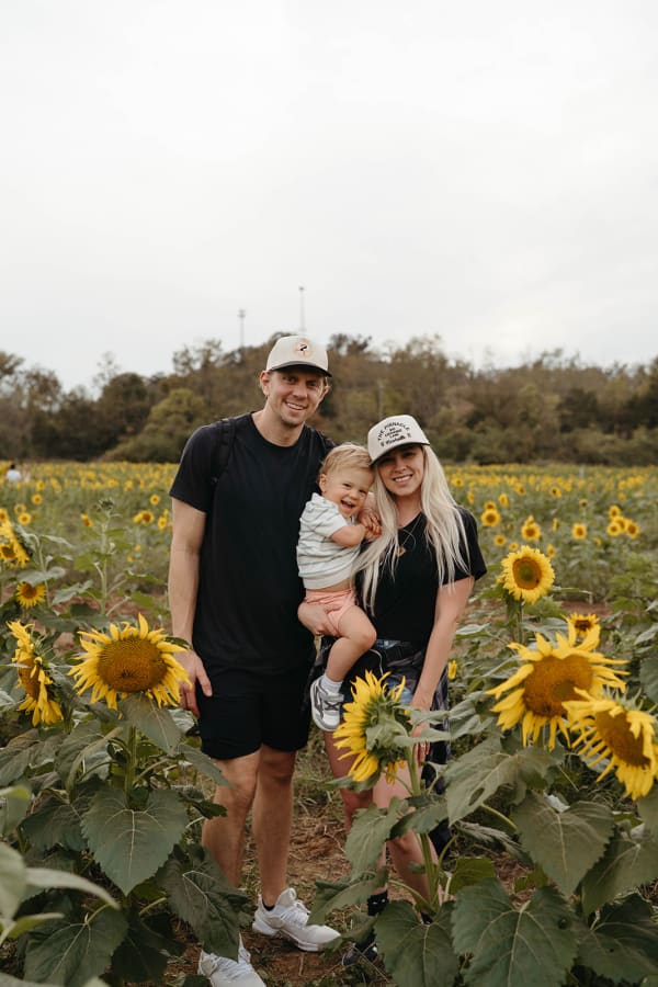 Family with a baby posing in the sunflowers
