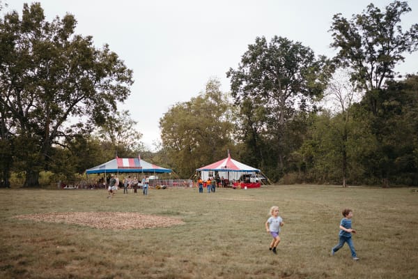Kids running across the field toward the tents